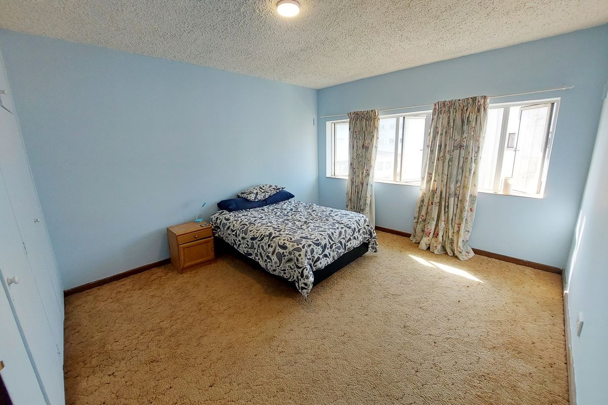 Spacious bedroom featuring wall-to-wall carpeting, large windows allowing natural light, and built-in closet storage.