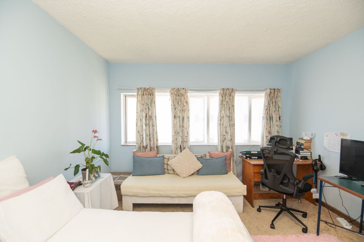 A bedroom featuring light blue walls, a textured ceiling, and large casement windows allowing natural light into the space.