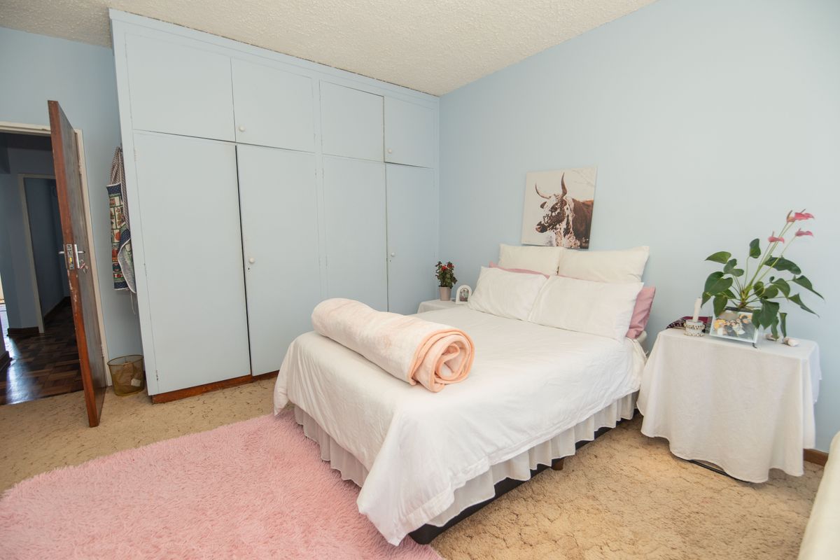 A bedroom featuring built-in cupboards and a textured ceiling, offering a functional space with potential for modern updates.