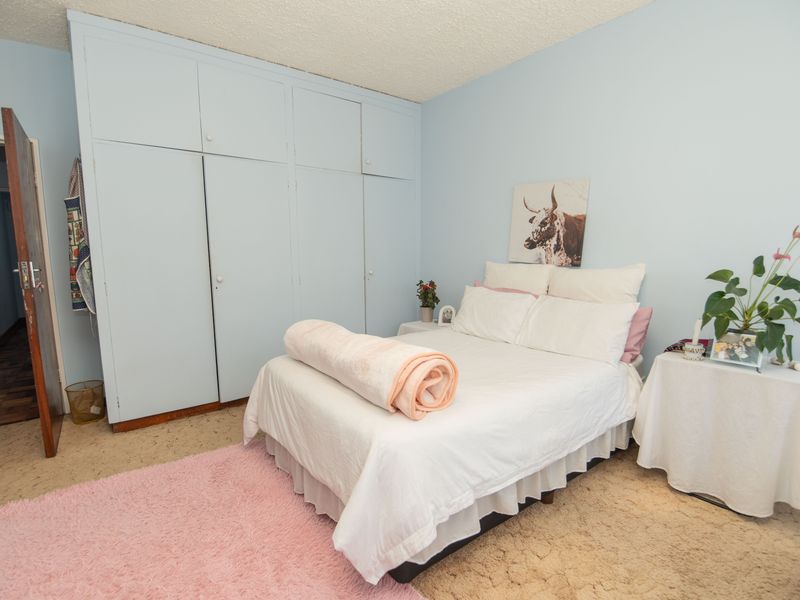 A bedroom featuring built-in cupboards and a textured ceiling, offering a functional space with potential for modern updates.