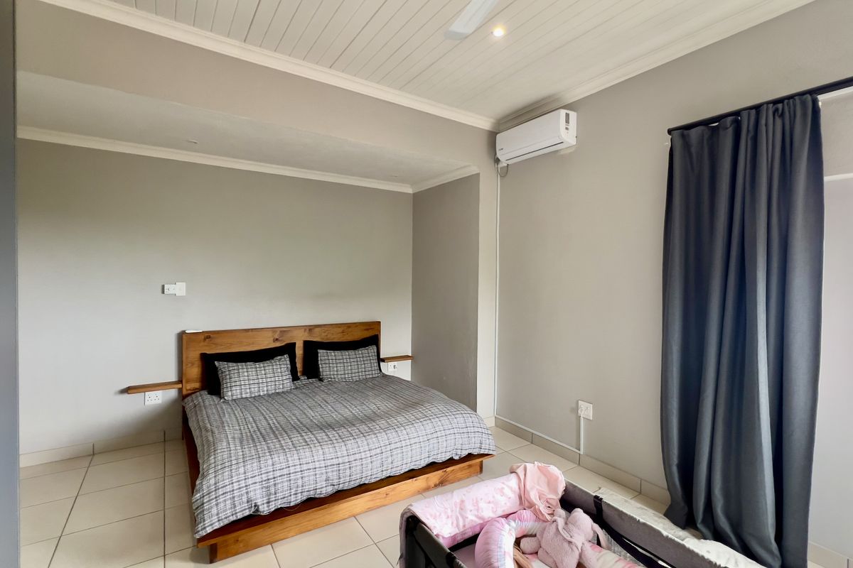A well-maintained bedroom featuring tiled flooring, a tongue-and-groove ceiling, and a wall-mounted air conditioning unit.