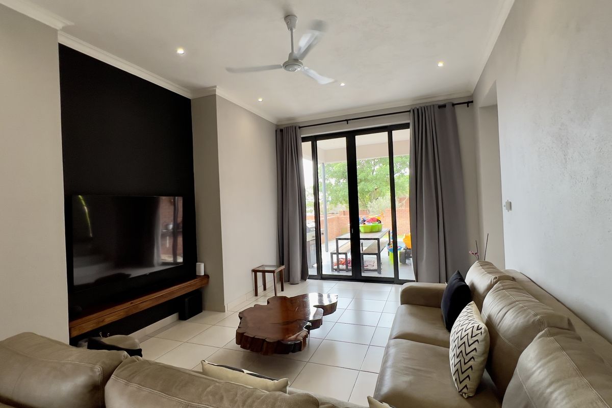 Spacious living room featuring tiled flooring, a ceiling fan, and large sliding glass doors providing direct access to the outdoor patio area.