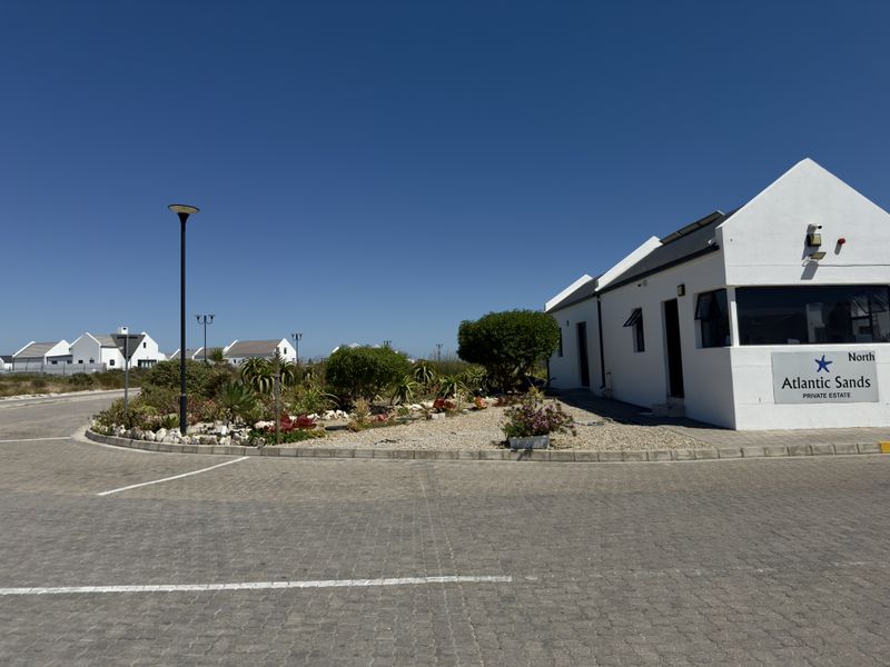 Entrance view of the Atlantic Sands Private Estate, featuring paved driveway, landscaped garden beds, and estate signage.
