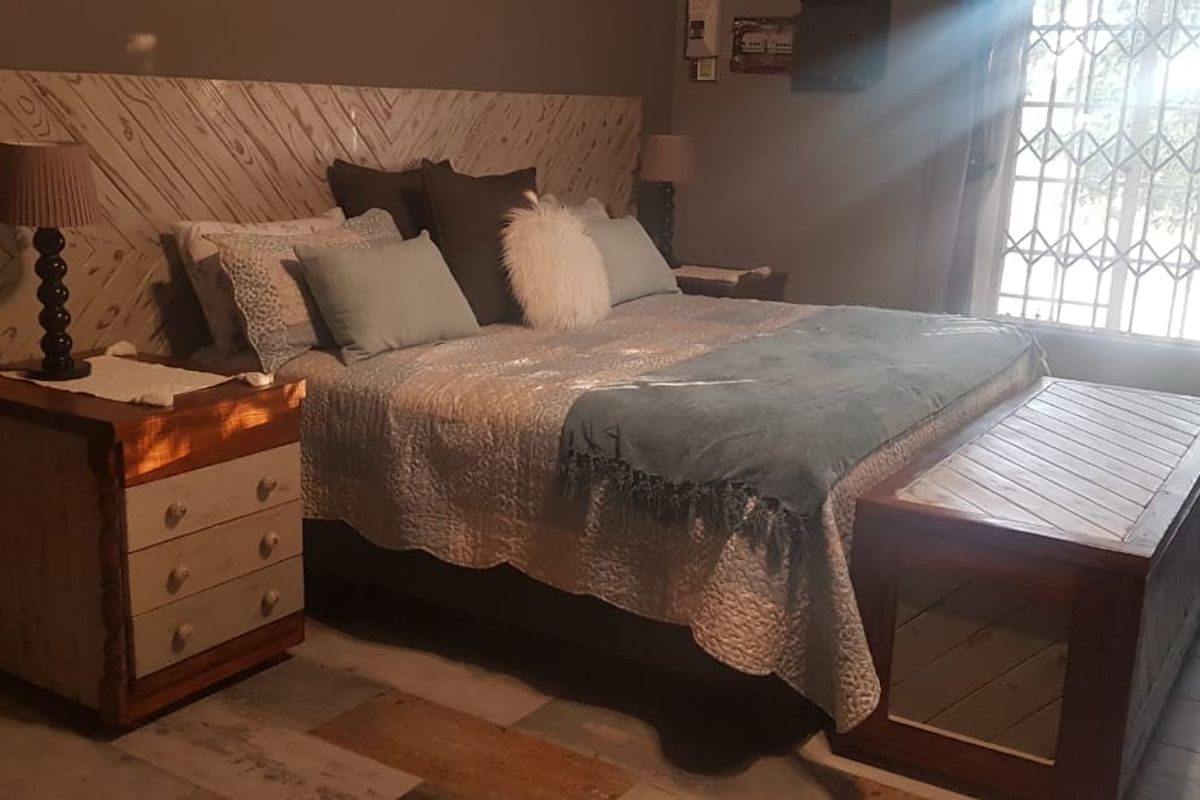 A cozy bedroom featuring a custom wooden headboard, tiled flooring, and a security gate on the window, providing a rustic and secure living space.
