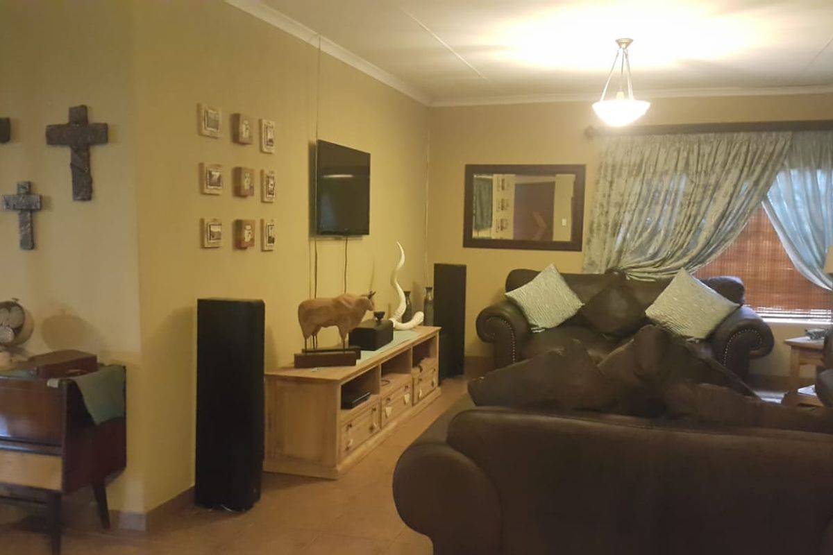 A comfortable living room featuring tiled flooring, neutral wall tones, and a large window with curtains, providing a functional and inviting space.