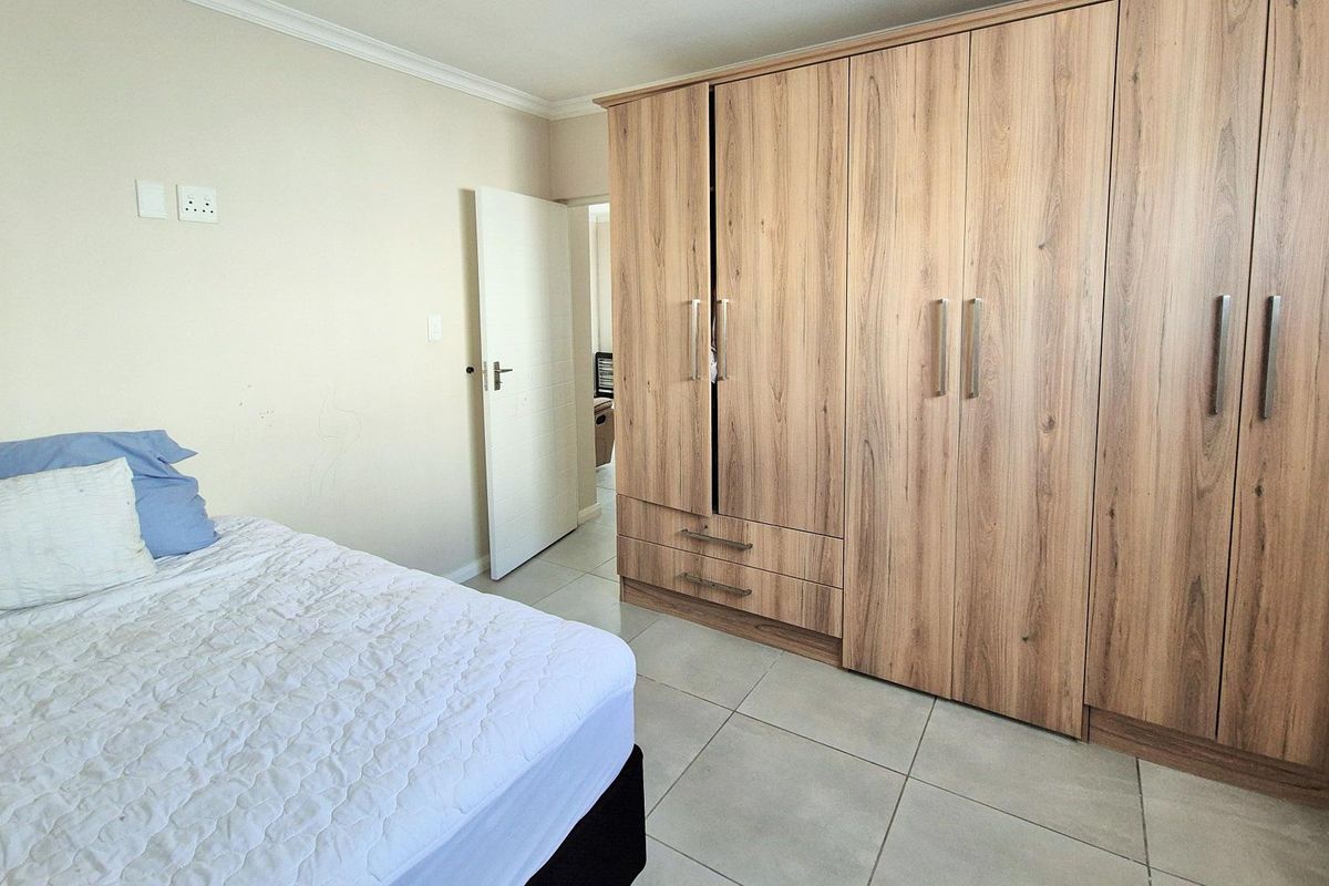 Bedroom featuring built-in wooden cupboards and tiled flooring.