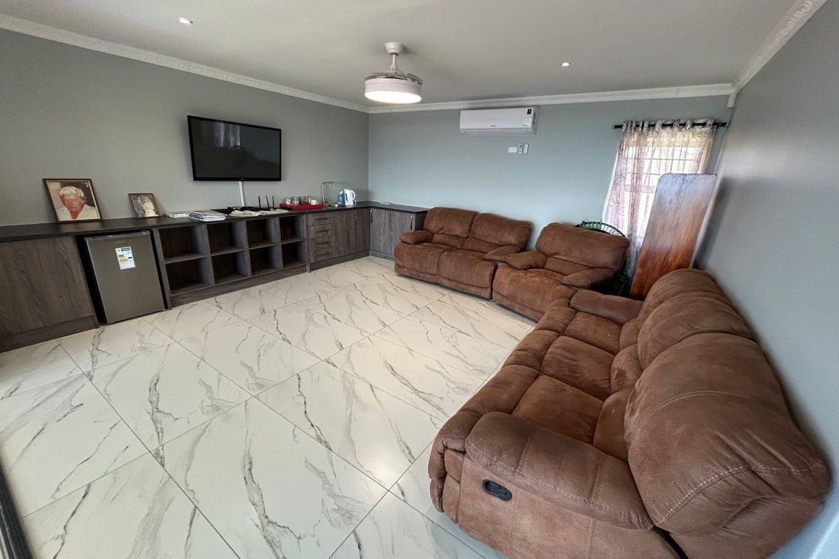 Spacious living room featuring marble-look floor tiles, built-in cabinetry, a ceiling fan, and a wall-mounted air conditioning unit.