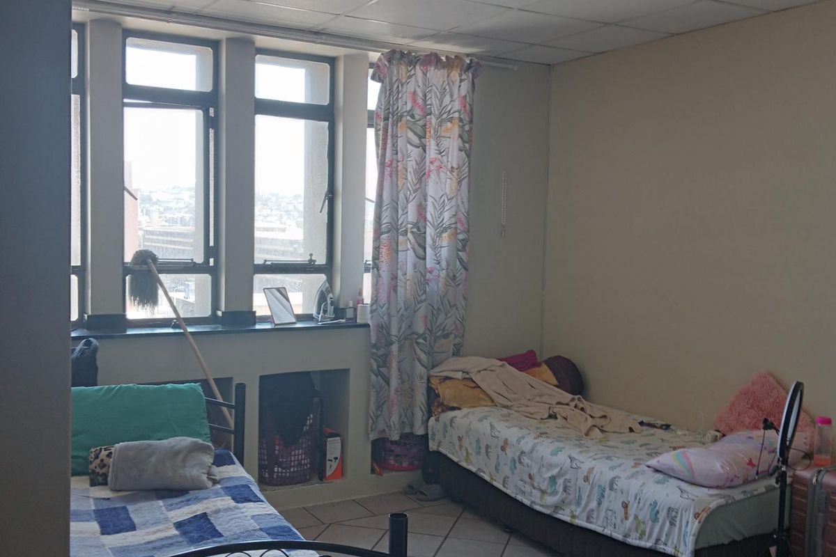 A bedroom featuring tiled flooring, a drop ceiling, and large windows with built-in storage niches.
