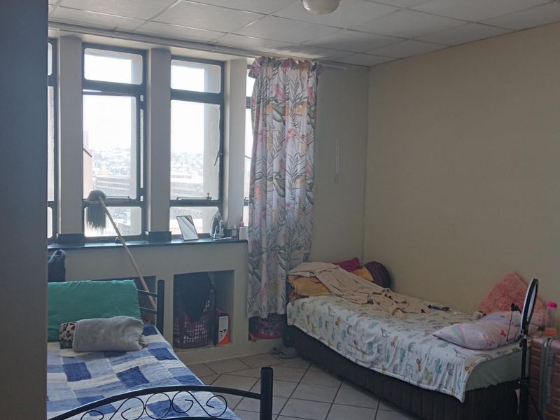 A bedroom featuring tiled flooring, a drop ceiling, and large windows with built-in storage niches.
