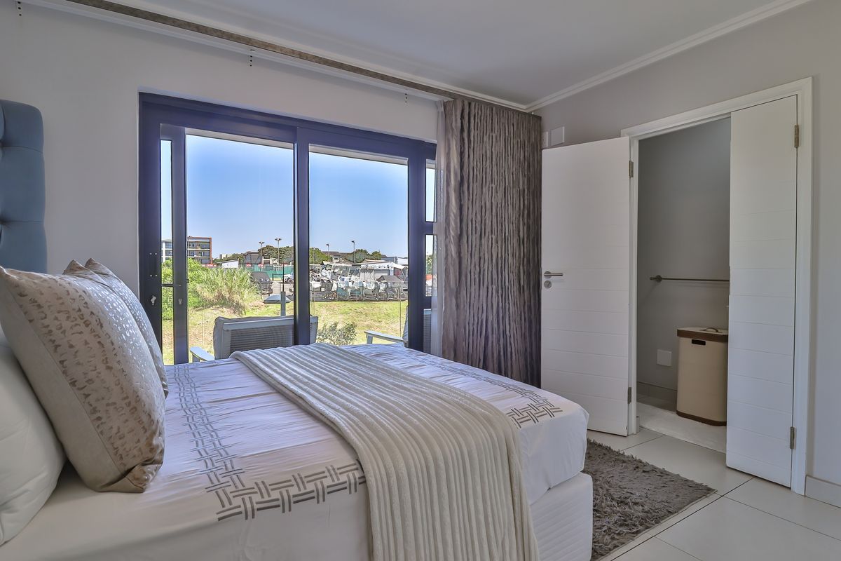 A bright bedroom featuring large sliding glass doors that open to an outdoor view, complemented by an adjoining en-suite bathroom with modern finishes.