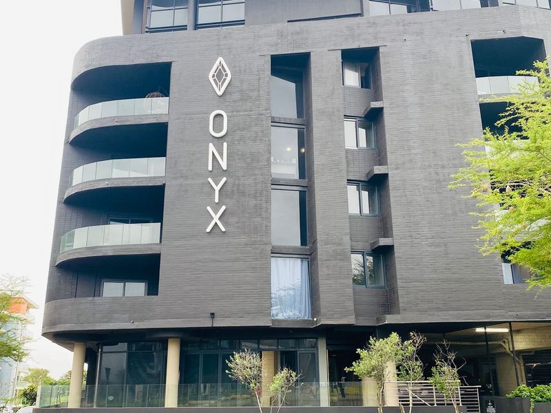 Modern multi-story apartment building facade featuring dark brickwork, glass balconies, and contemporary architectural design.