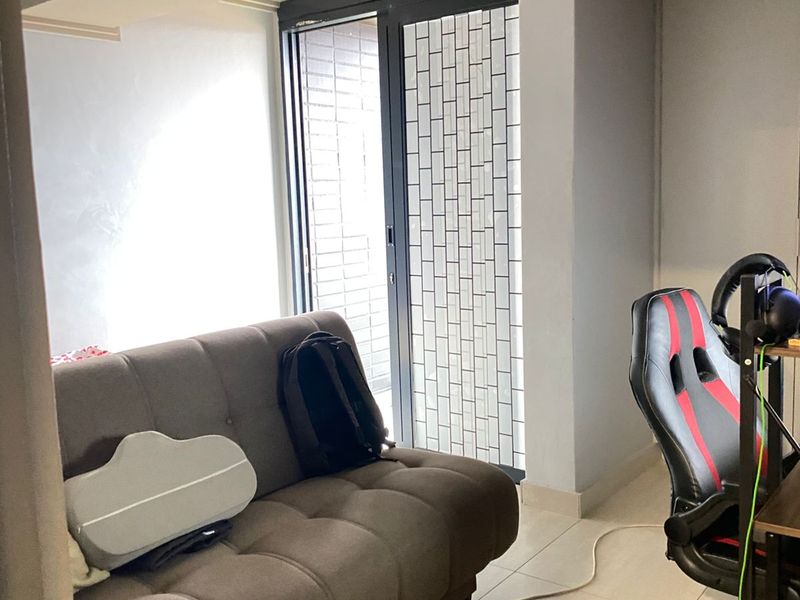 A functional living room space featuring tiled flooring and a glass sliding door providing access to an outdoor area.