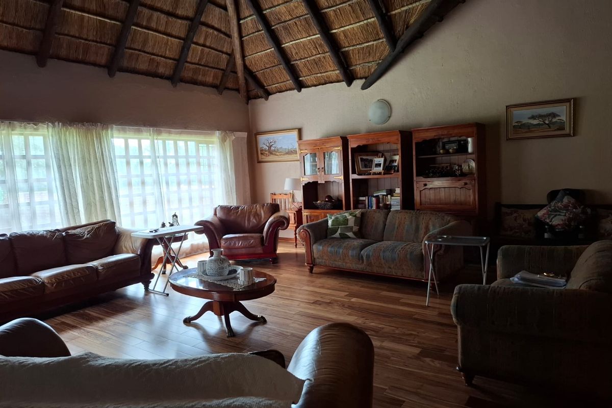Spacious living area featuring a high vaulted thatched ceiling, exposed timber beams, and warm wood-look flooring, creating a rustic and inviting atmosphere.