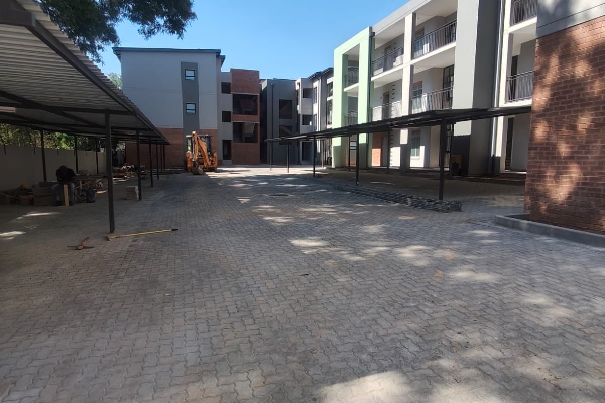 A view of the apartment complex exterior featuring paved parking areas with covered carports and modern multi-story building facades.