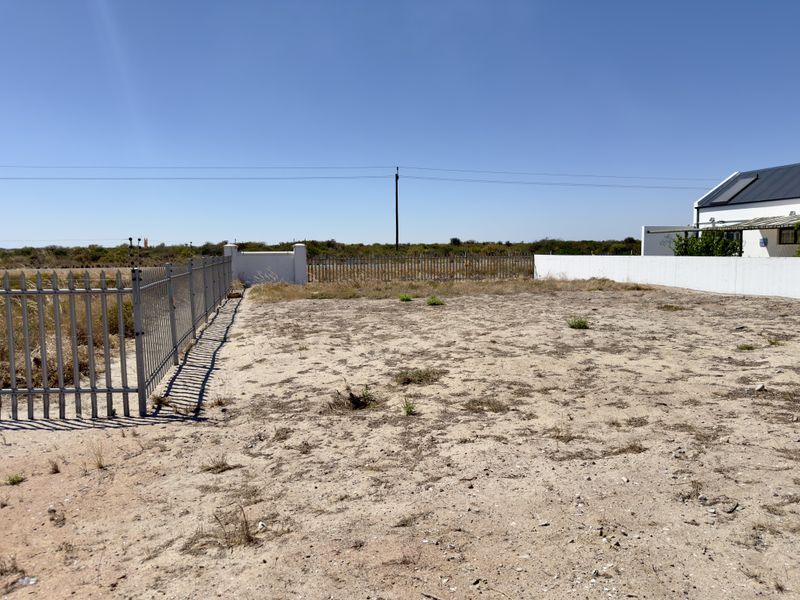 A vacant residential plot featuring perimeter metal fencing and boundary walls, offering a blank canvas for future development.