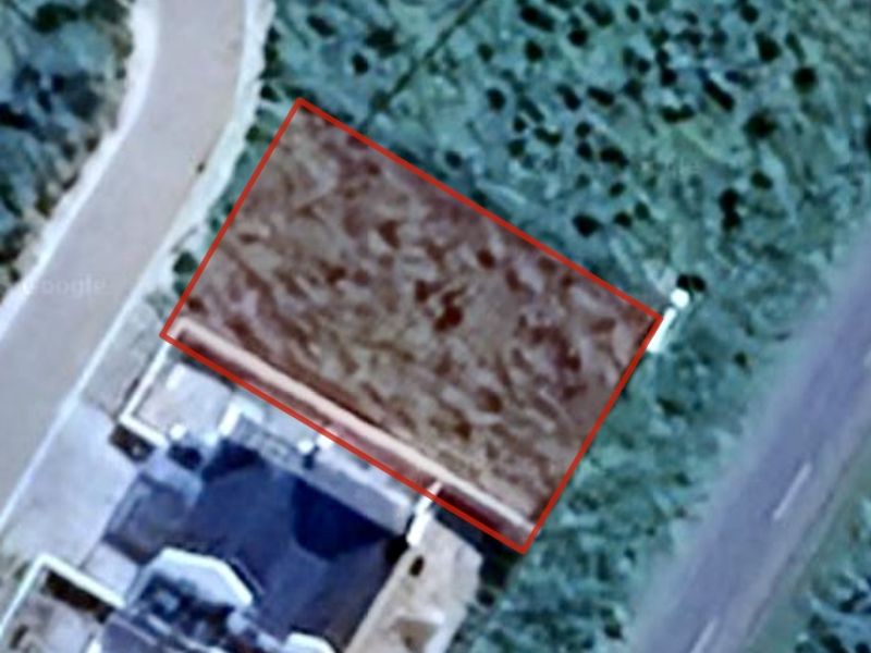 An aerial view of a vacant residential plot, highlighting the property boundaries and surrounding landscape.