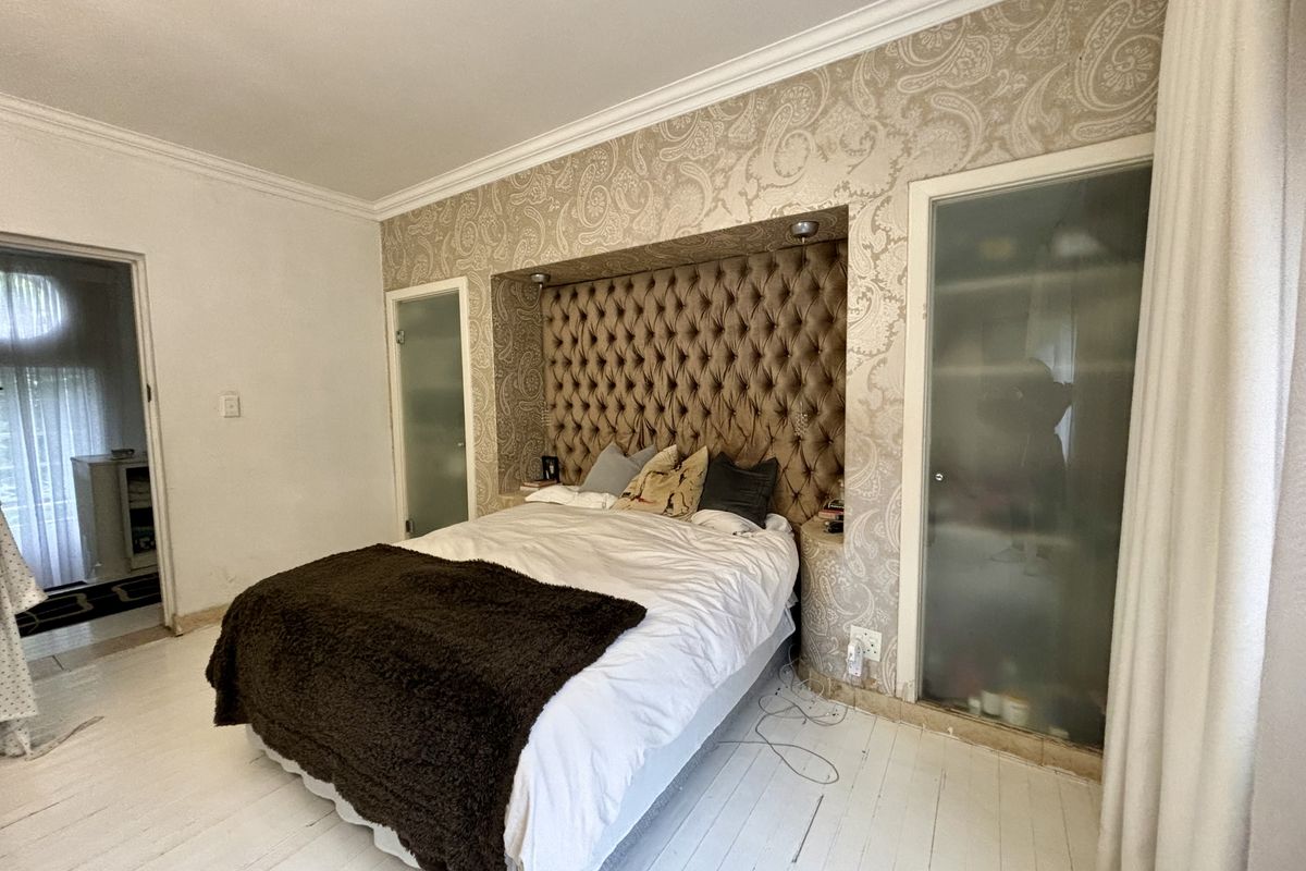 Bedroom featuring a tufted built-in headboard, recessed lighting, and integrated storage with frosted glass doors.