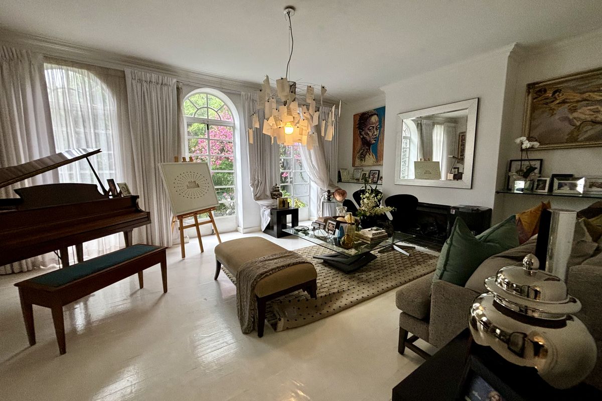 Spacious living room featuring elegant arched windows, polished hardwood flooring, and a central fireplace, creating a bright and inviting atmosphere.