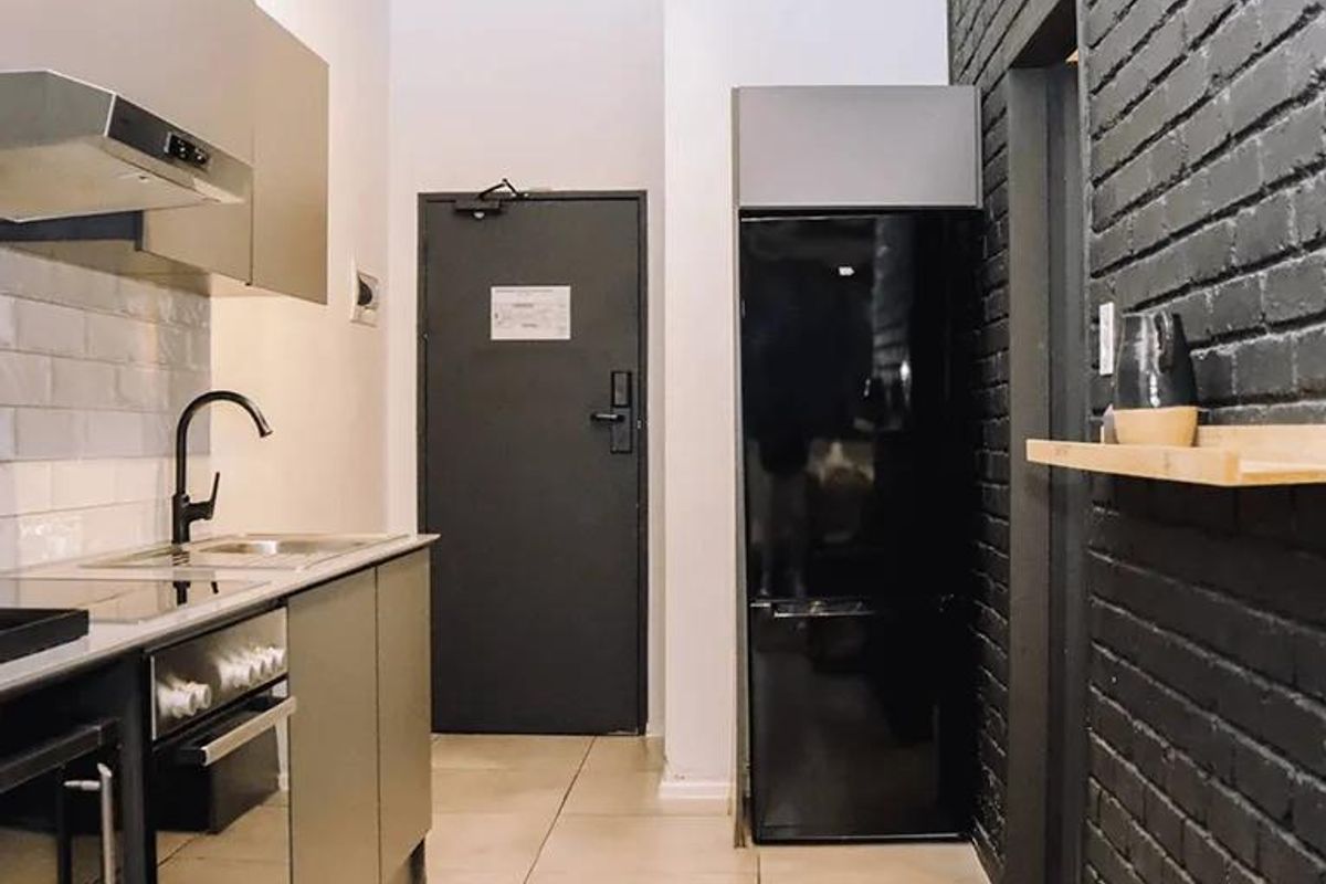 Modern kitchen featuring sleek cabinetry, integrated appliances, subway tile backsplash, and a striking black brick feature wall.