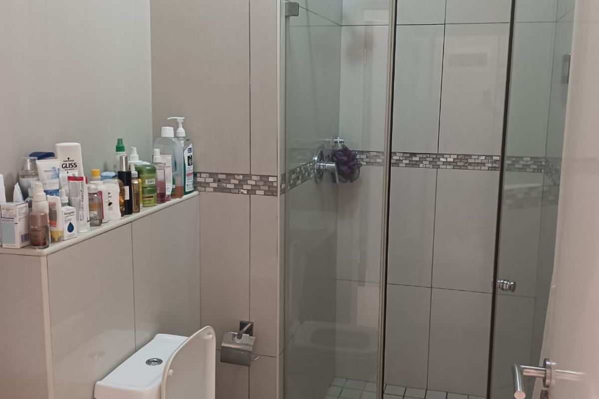 Modern bathroom featuring a glass-enclosed walk-in shower, tiled walls, and a wall-mounted toilet with a built-in cistern.