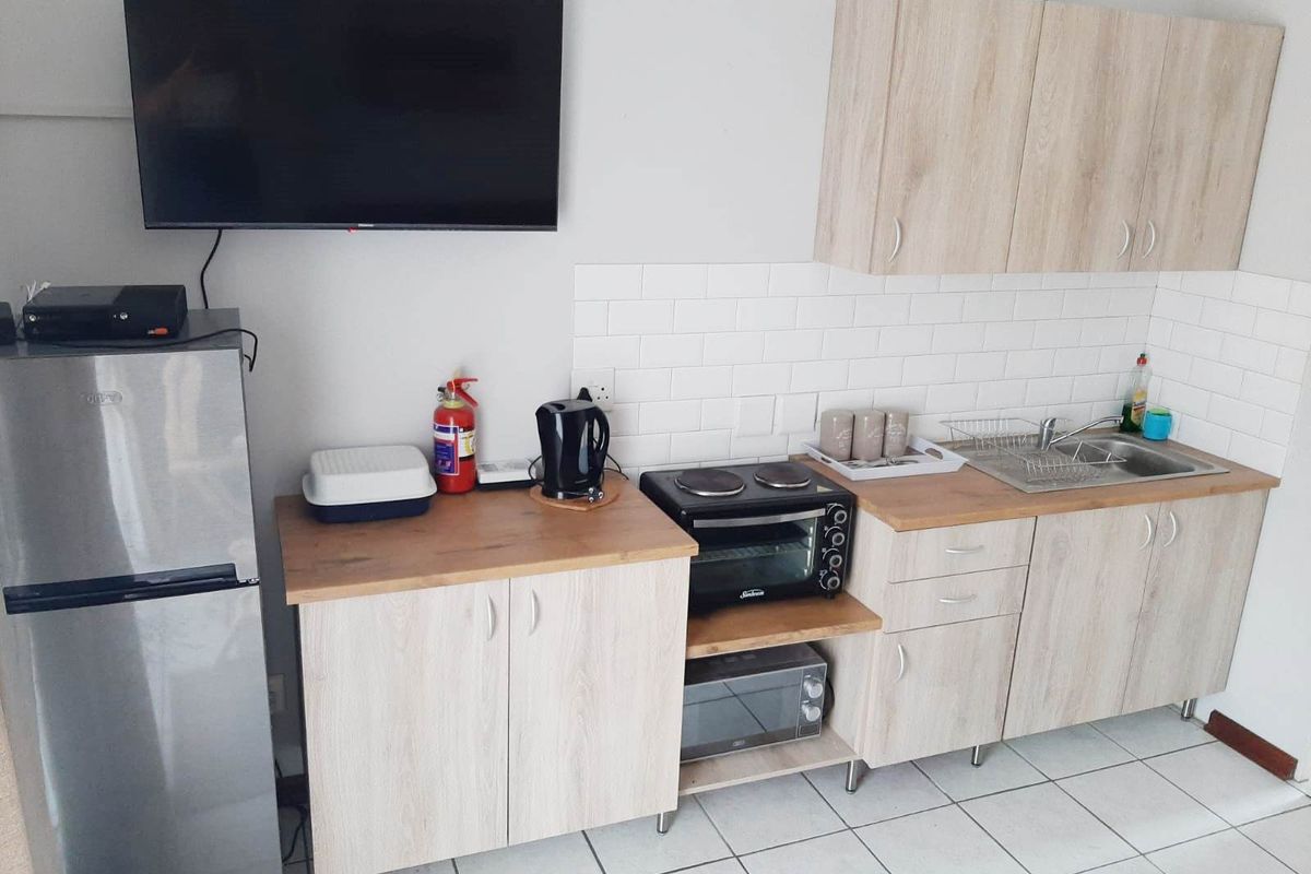 Compact kitchenette featuring light-wood cabinetry, subway tile backsplash, laminate countertops, and a stainless steel sink, providing functional preparation space.
