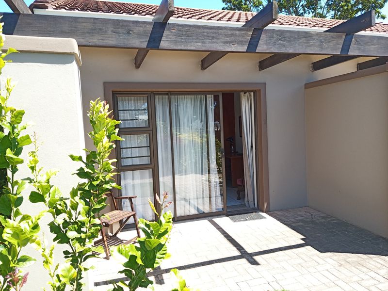 A private paved patio area featuring a timber pergola and sliding glass door access to the interior living space.