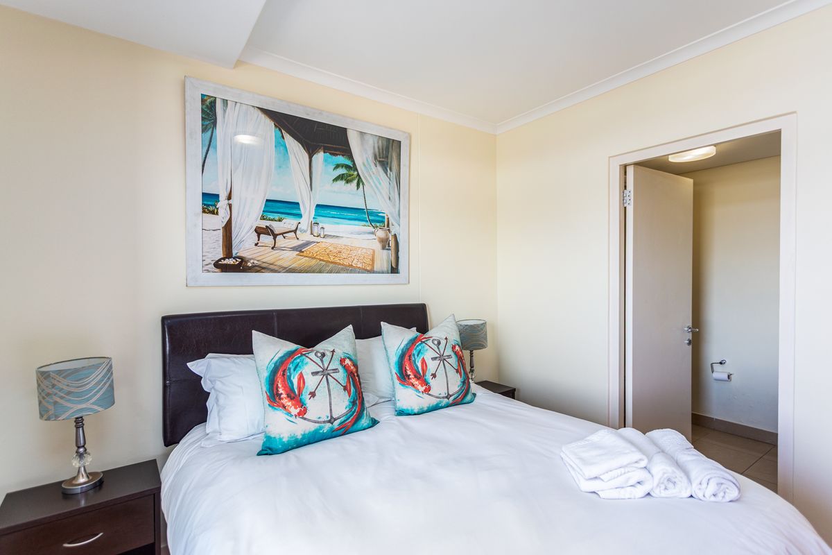 A bedroom featuring neutral walls, coved ceilings, and an adjoining doorway leading to a bathroom area.