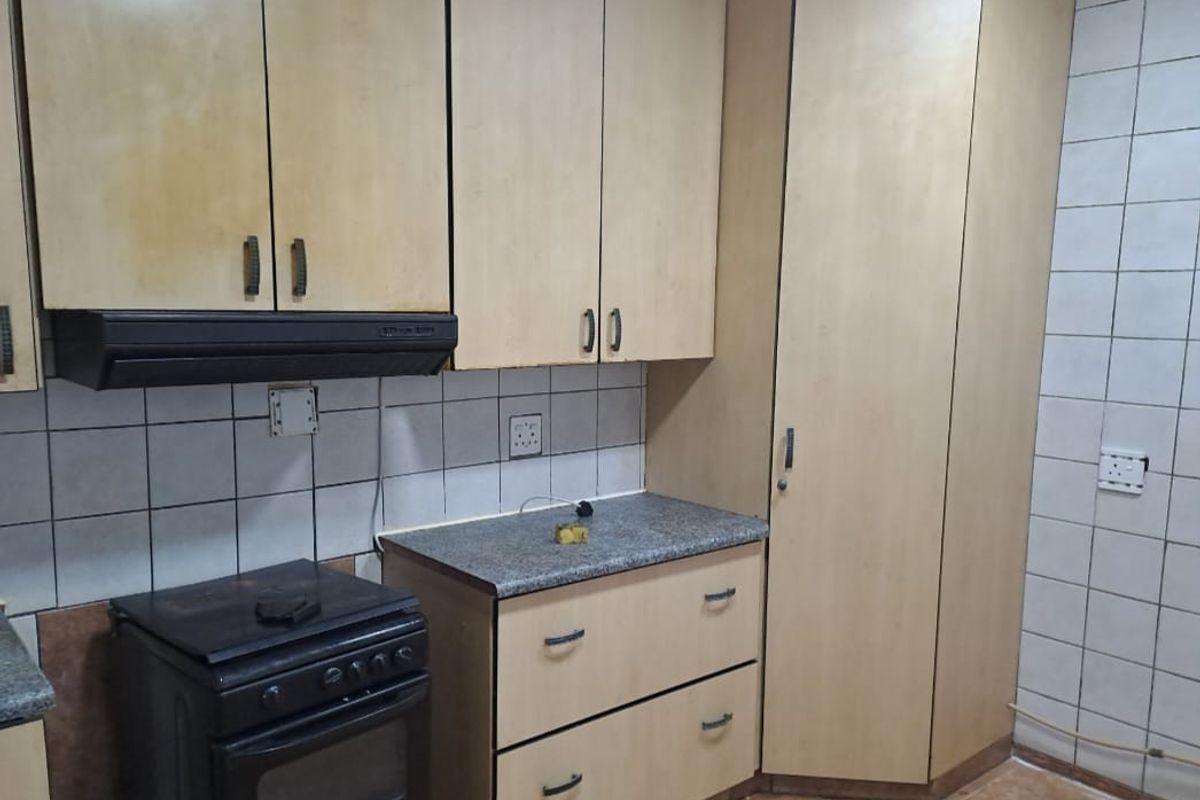 A functional kitchen featuring light wood-tone cabinetry, a tiled backsplash, and a built-in stove with an extractor fan.