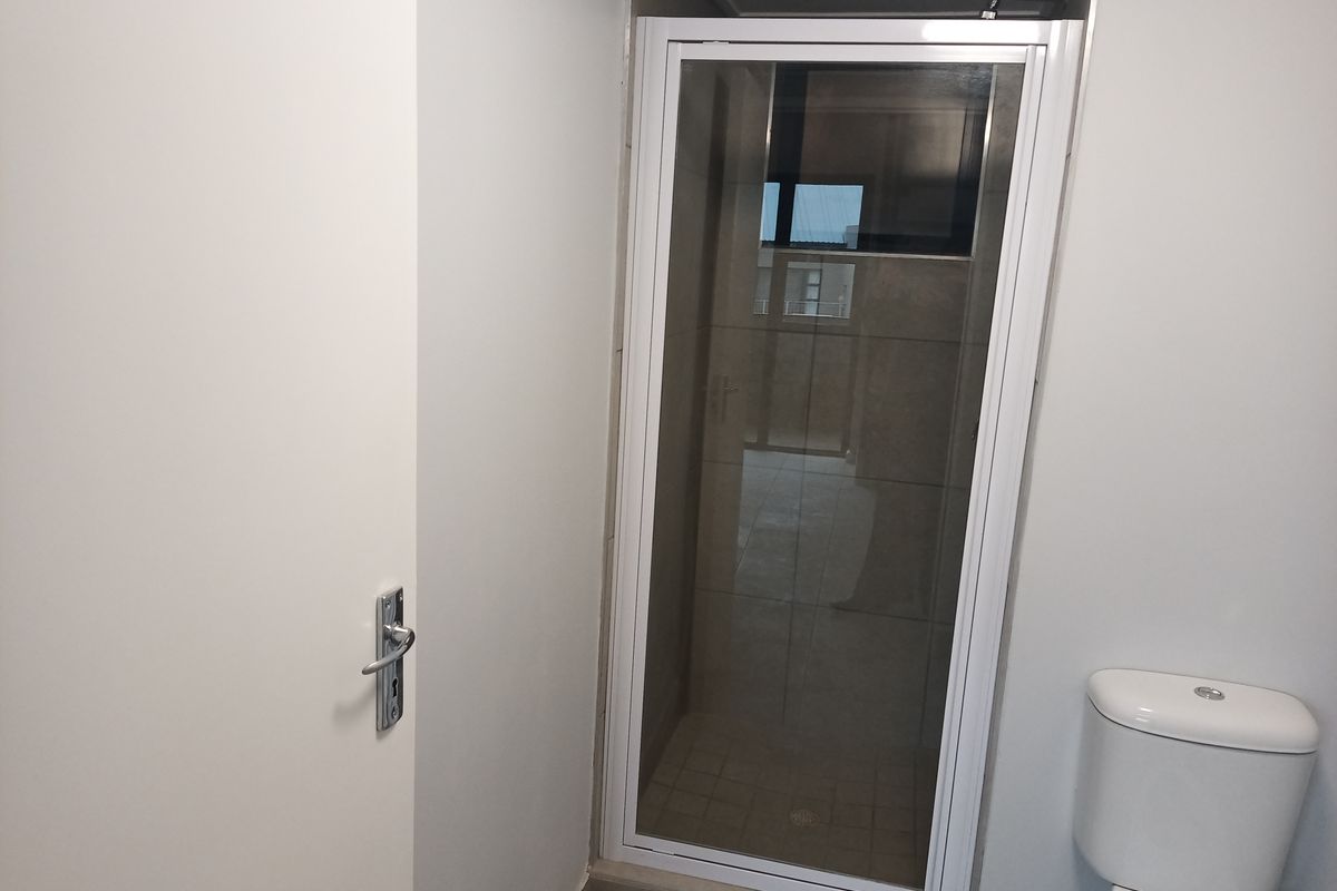 A clean, functional bathroom featuring a shower enclosure with a white frame and a standard toilet.
