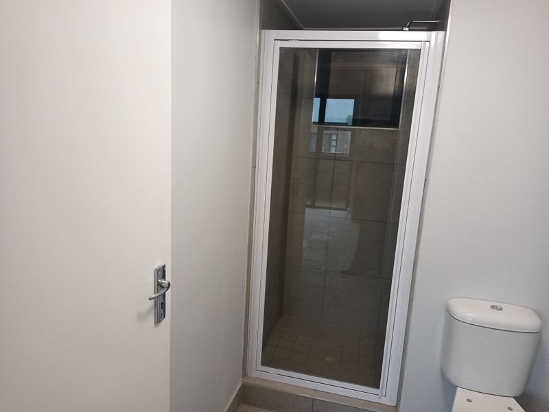 A clean, functional bathroom featuring a shower enclosure with a white frame and a standard toilet.
