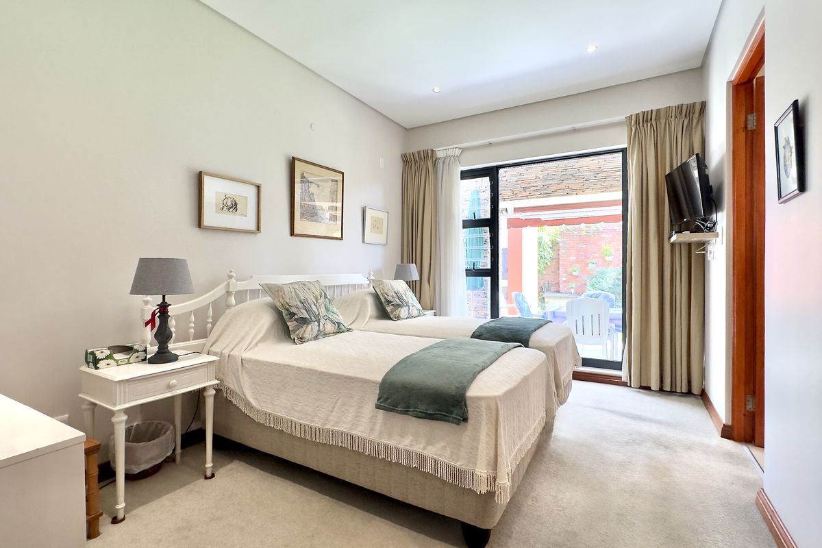 A well-maintained bedroom featuring neutral carpeting, recessed lighting, and a sliding glass door providing direct access to an outdoor patio area.