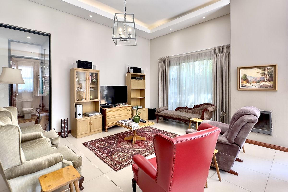 Spacious living room featuring high ceilings with recessed lighting, large windows with curtain tracks, and a built-in fireplace.