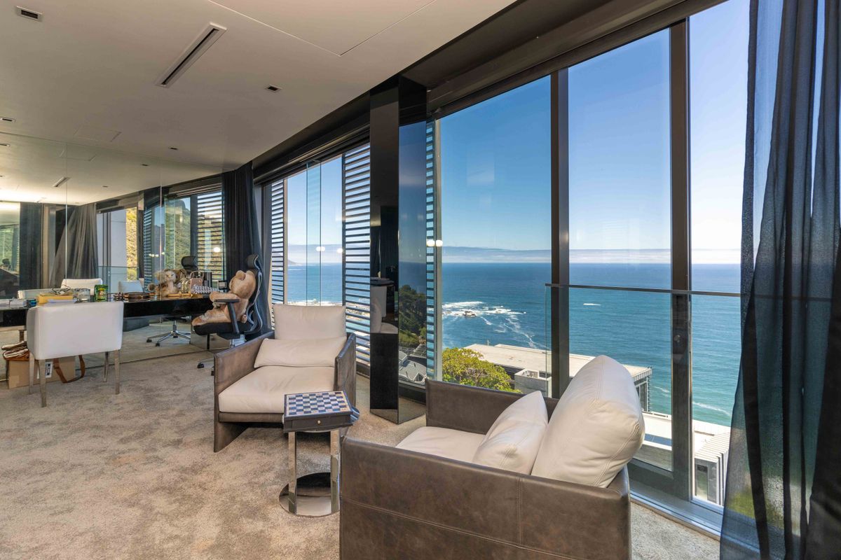 A modern living area featuring floor-to-ceiling glass windows with expansive ocean views, recessed ceiling lighting, and high-quality finishes.