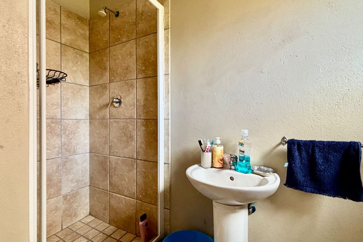 A functional bathroom featuring a pedestal basin and a tiled shower enclosure with a glass door.