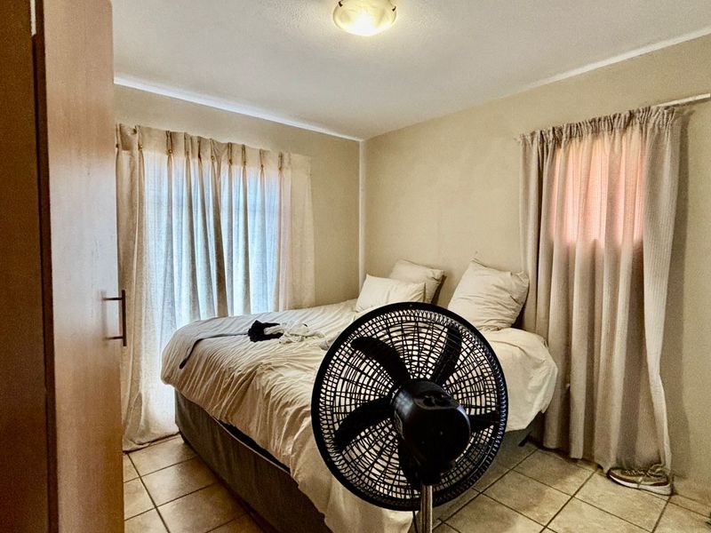 A functional bedroom featuring tiled flooring and a built-in cupboard, offering a neutral canvas for potential updates.