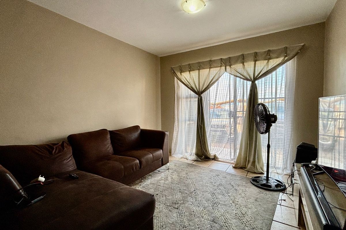 A living room featuring tiled flooring and a sliding glass door providing natural light.