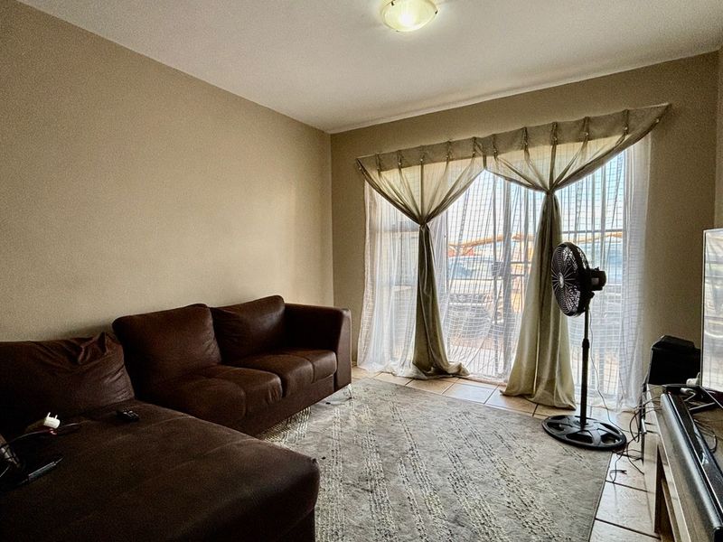 A living room featuring tiled flooring and a sliding glass door providing natural light.