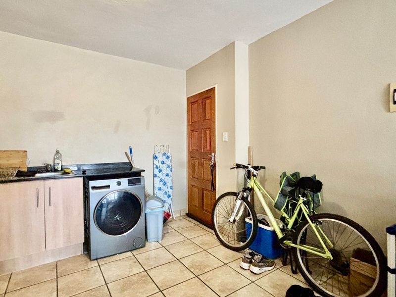 A functional laundry area featuring built-in cabinetry, a sink, and tiled flooring, providing a practical space for household utility tasks.