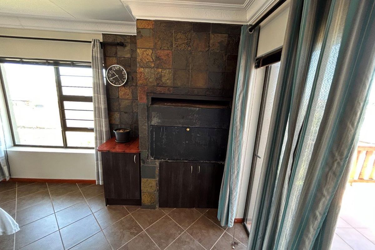 Living area featuring a built-in fireplace with stone tile surround, tiled flooring, and direct access to an outdoor patio through sliding glass doors.