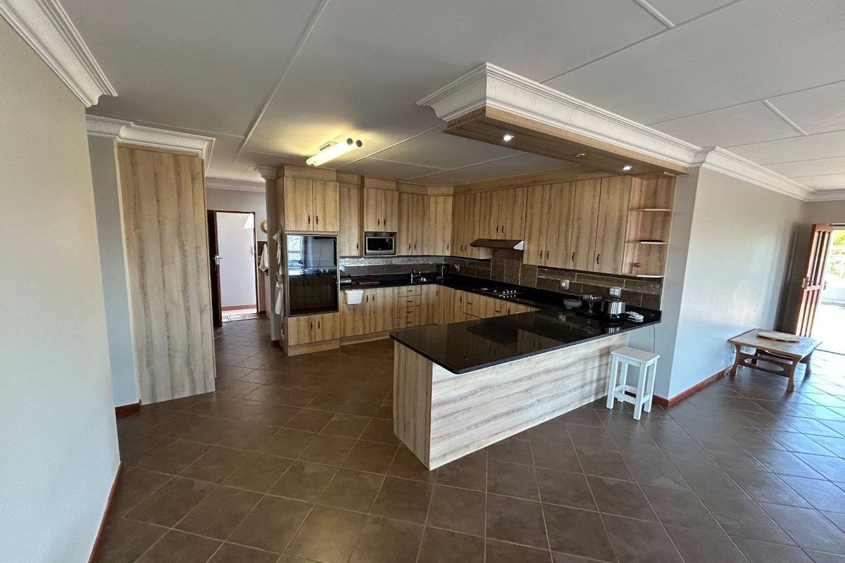 A well-maintained kitchen featuring wood-finish cabinetry, granite countertops, built-in appliances, and tiled flooring with a breakfast bar area.