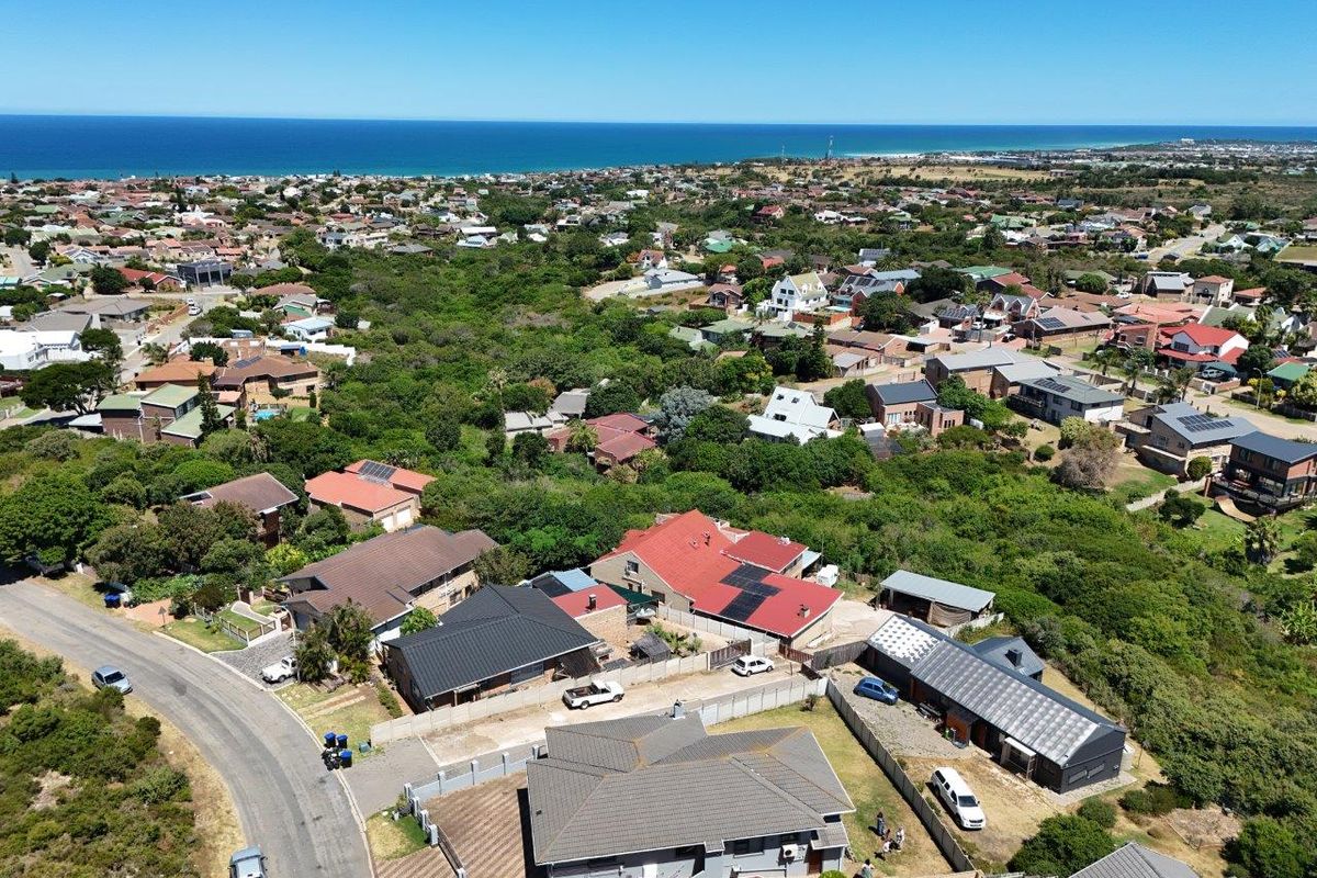 An aerial view of a coastal residential neighborhood, showcasing the property's location, surrounding homes, and proximity to the ocean.