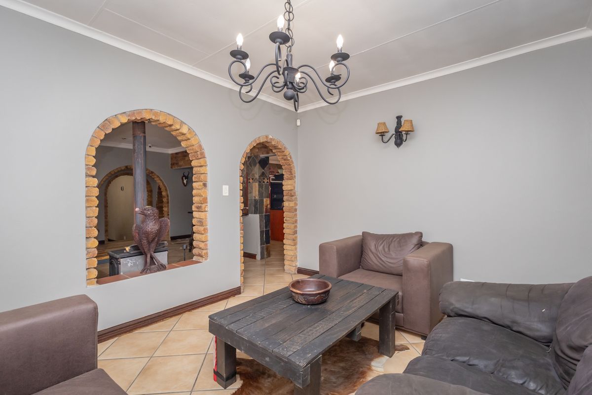 Living room featuring distinctive brick-arched openings, a central chandelier, and tiled flooring, providing a unique architectural character to the space.