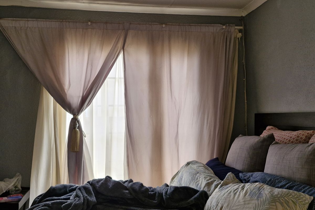 A bedroom featuring a window with curtain treatments and textured wall finishes.