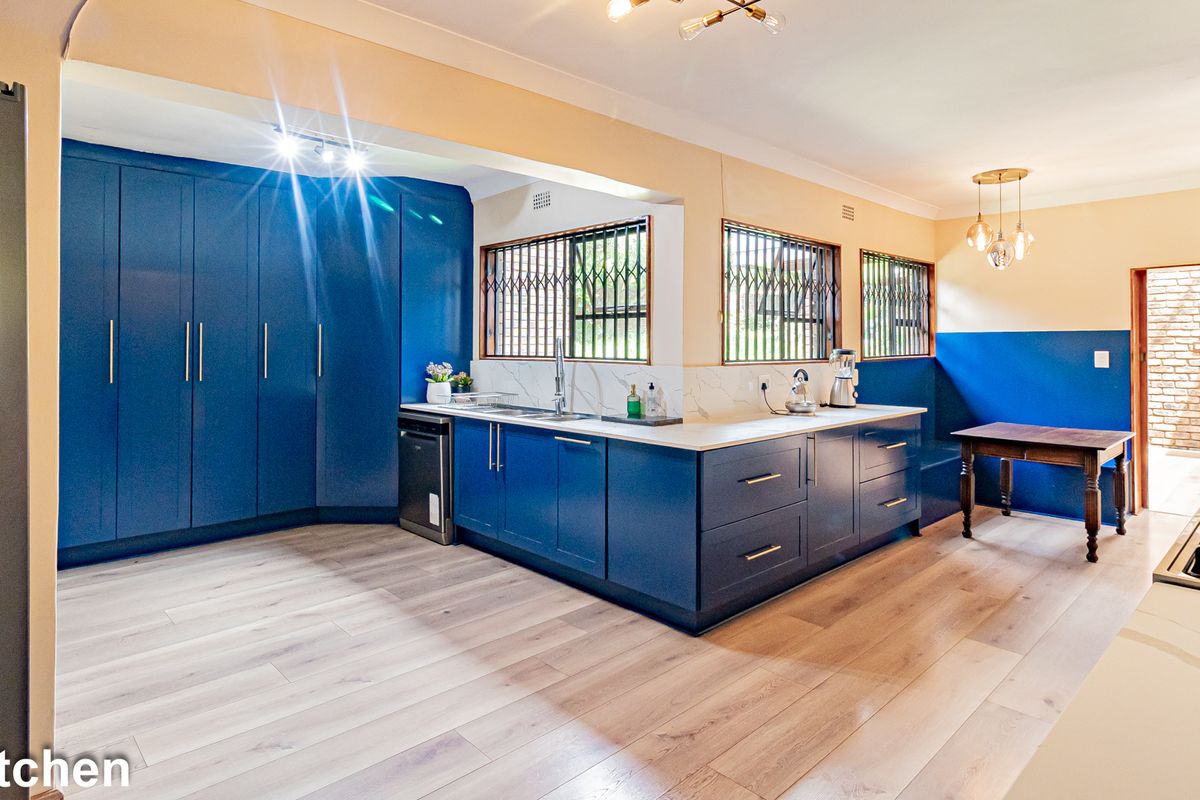 Modern kitchen featuring blue cabinetry, stone countertops, integrated sink, and light wood-look flooring, offering a clean and contemporary aesthetic.