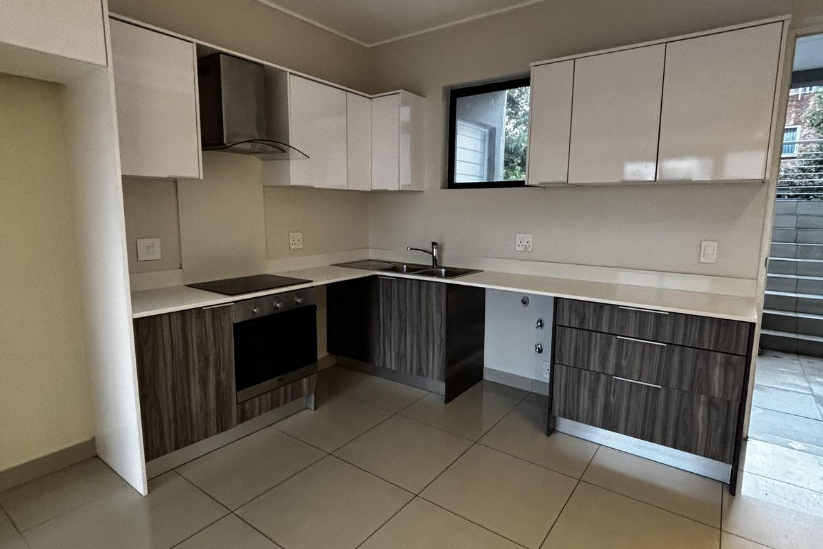 Modern kitchen featuring two-tone cabinetry, stone countertops, integrated oven, hob, and extractor fan with tiled flooring and recessed ceiling lighting.