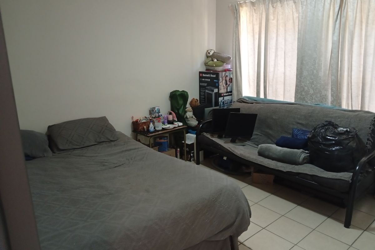 A bedroom featuring tiled flooring and window curtain rails, providing a functional space for rest.