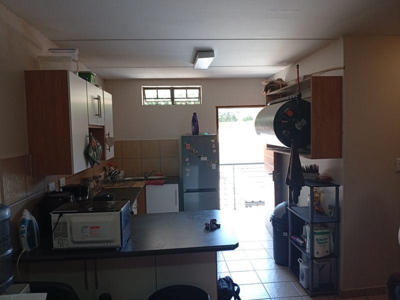 A functional kitchen area featuring built-in cabinetry, tiled backsplash, and direct access to an outdoor balcony area.