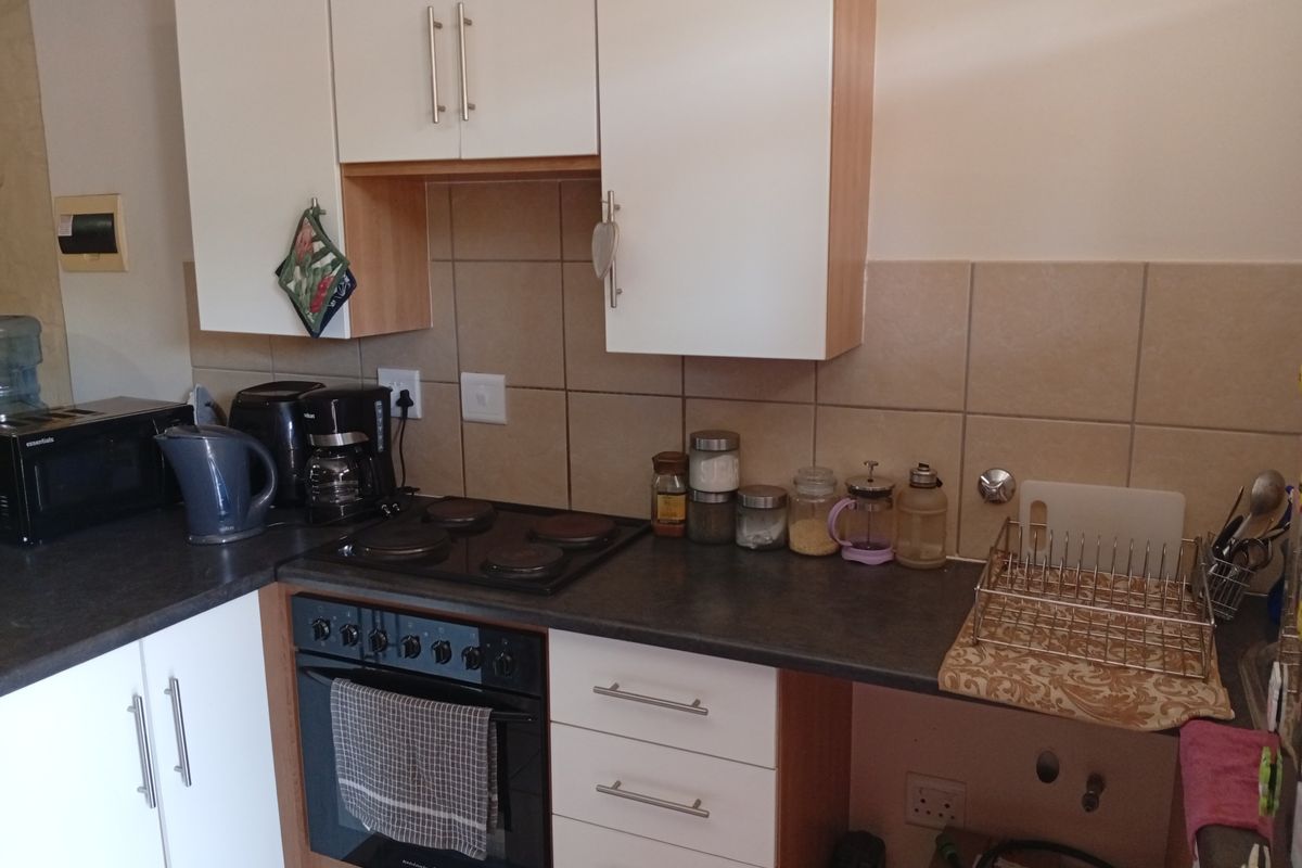 A functional kitchen featuring built-in cabinetry, laminate countertops, an electric hob, and an integrated oven with tiled backsplash.