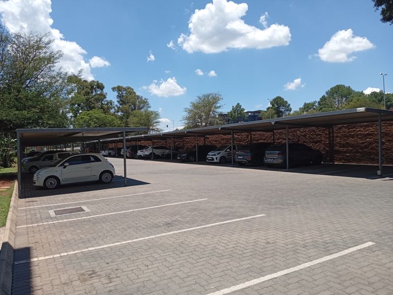 A well-maintained outdoor parking area featuring covered bays with paved surfaces and a brick retaining wall.