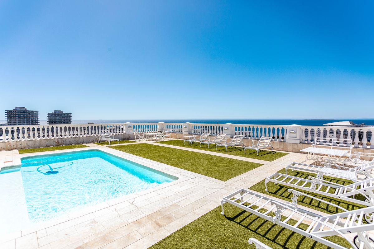 Spacious rooftop pool area featuring a swimming pool, artificial turf, and a classic balustrade with panoramic ocean views.